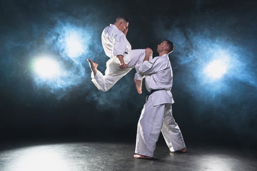Martial arts masters on dark background. Strong man fighters in white kimono for karate martial arts fighting training in black gym. Karate fighters training punches kicks practicing fight sparring photo