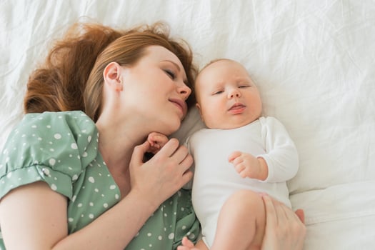 Happy family at home. Mother playing with little toddler child on bed. Mom baby relax playing having fun together. Mother looks at baby with love care. Mom of breast feeding baby rest in living room photo