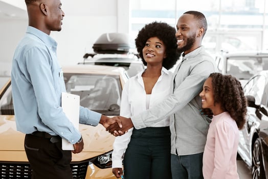 Happy Afro family shaking hands with car salesman, making auto purchase agreement at dealership. Black parents with daughter buying new vehicle at automobile showroom store photo