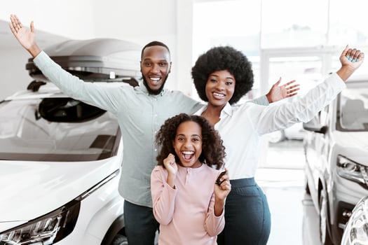 Visiting car dealership. Excited Afro family showing key, shouting WOW, feeling overjoyed about buying new auto, looking at camera, raising hands up at automobile showroom photo