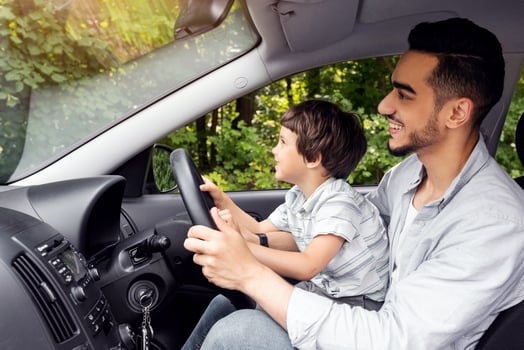 Happy smiling muslim young male teaches small kid how to drive, profile. Dad and son got drive lesson, new car, auto safety, life insurance, study at free time together. Love and family relationships photo