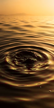 Rippling water surface reflecting golden hues, with a central disturbance creating circular waves photo