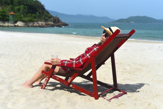 Young woman in hat sitting on the desk chair at the beach with white sand in Vietnam photo