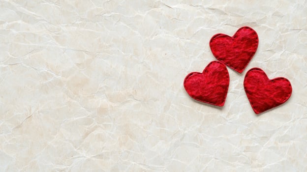Three red hearts on crumpled paper background photo