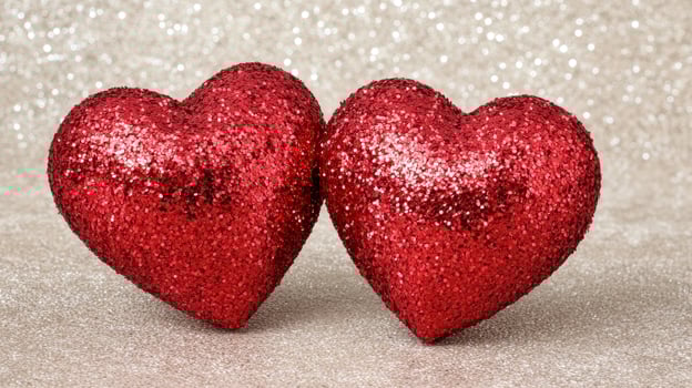 Two red glitter hearts on a sparkling background photo