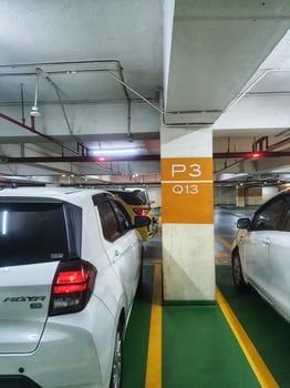 Jakarta, Indonesia on 21 March 2024. Underground Parking Lot Cars Parked Near Orange Sign photo