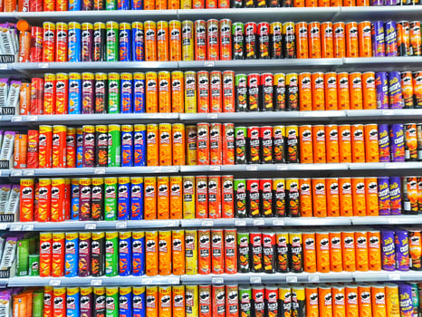 Madinah, Saudi Arabia on 28 February 2024. Colorful Snack Chip Cans Grocery Store Shelf Display photo