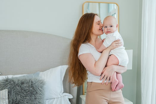 Happy family at home. Mother holding little toddler child daughter. Mom and baby girl relax playing having fun together at home. Mother hugs baby with love care. Mom of breast feeding baby photo