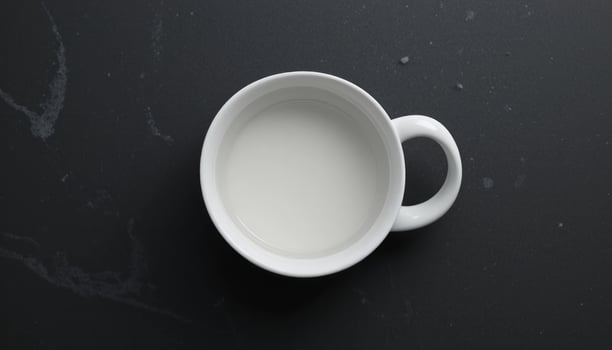 Overhead Shot of a White Mug Filled with Creamy Liquid on a Dark Marble Surface photo