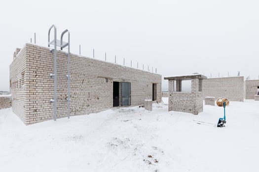 Winters Pause A Brick Building Emerges Amidst the Snowy Silence, Surrounded by Tools and Materials Awaiting the Craftsmans Touch. photo