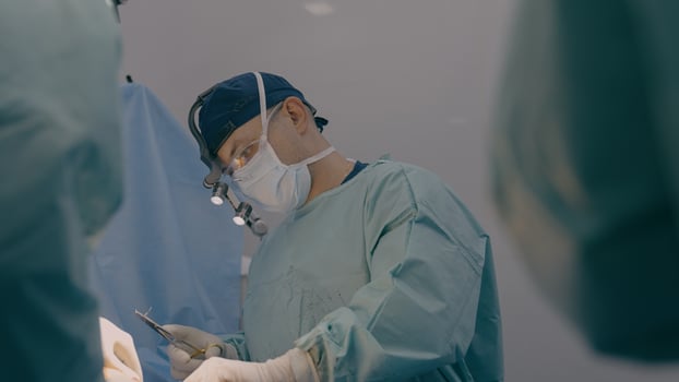 Surgeon man practitioner with team assistants perform surgical operation doctor sewing up wound sutures skin with medical tools clips thread in hospital operating room patient health treatment surgery photo