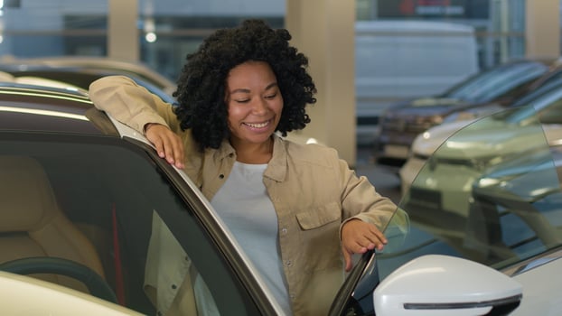 Happy customer client African American woman businesswoman girl buying new car enjoy luxury purchase in auto dealership female owner buy rent vehicle modern electric automobile looking camera laughing photo