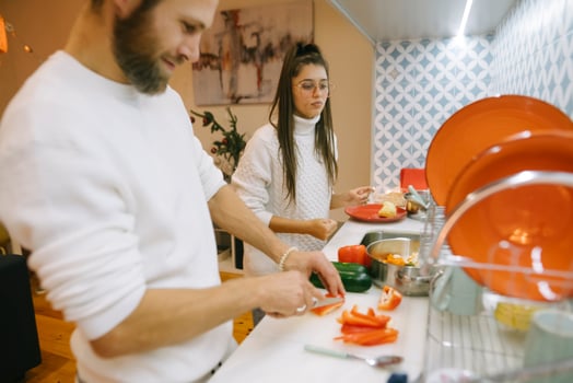 A couple happily cooking together in a modern kitchen filled with colorful ingredients and tools photo