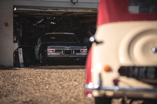 Vintage old car on a background of a garage where is another German luxury car is positioned. West Sussex, UK. photo
