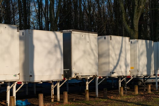 Several white storage car containers are neatly arranged in a wooded photo