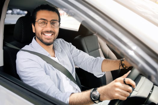 Handsome stylish middle-eastern man driving nice auto, looking through car window and smiling at camera, going to office or travelling alone by automobile, closeup photo, copy space photo