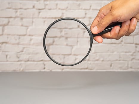Magnifier in hand with white brick wall background photo