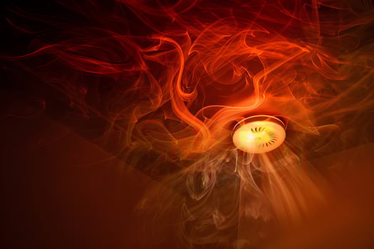 Dramatic smoke patterns spiraling from ceiling smoke detector for fire safety awareness photo