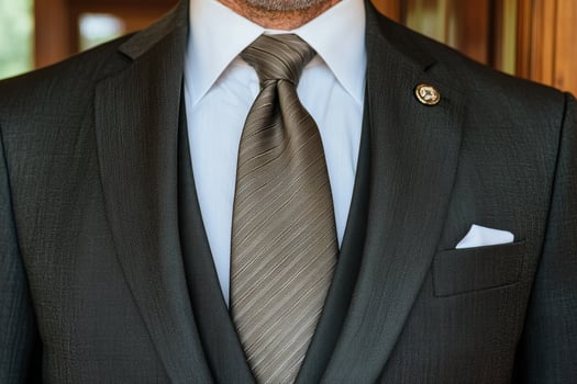 Close up of a man in a dark gray suit and brown tie photo