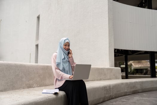 Muslim woman in hijab on a business call while working on her laptop photo
