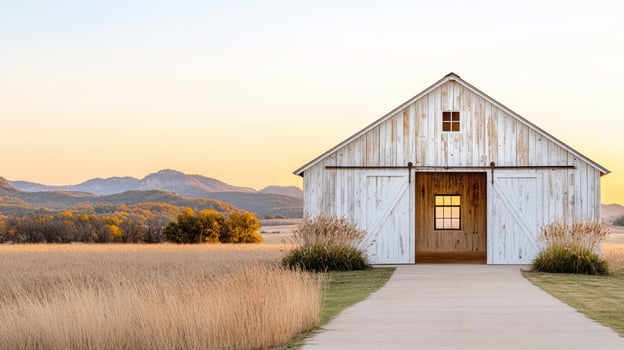A white barn sits in the middle of a field photo