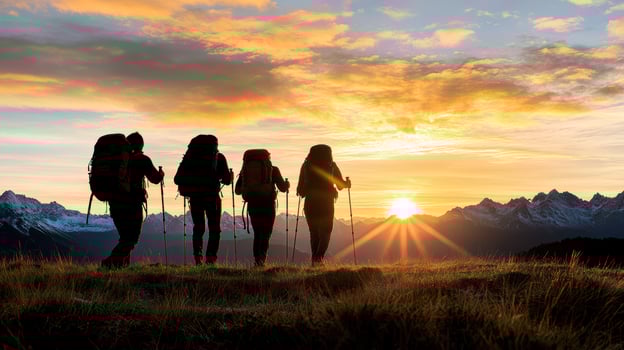 Four people with backpacks standing on a hill at sunset photo