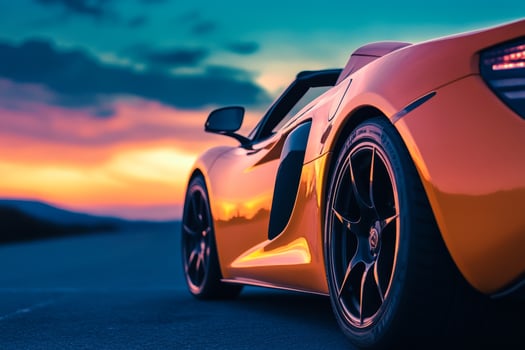 a modern sports car with orange body, standing against the background of a deep blue evening sky photo