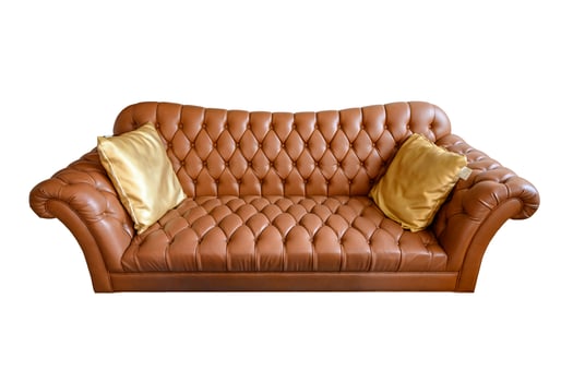 Orange vintage leather sofa buttoned with golden pillows. Isolated on background photo