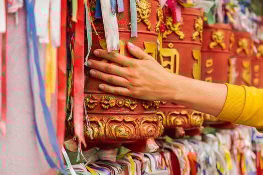 Person pilgrim female hand touching turning spinning Buddhist prayer wheel at Buddhist monastery. Prayer wheels in Buddhist stupa temple. Buddhism religion concept photo