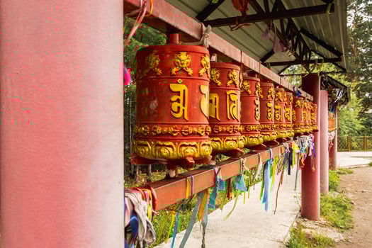 Rotating religious elements for touching turning spinning Buddhist prayer wheel at Buddhist monastery. Prayer wheels in Buddhist stupa temple. Buddhism religion concept photo