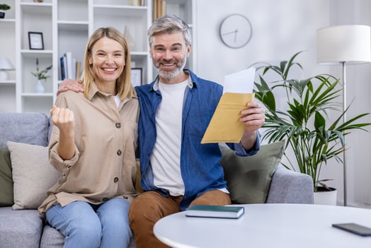 Joyful couple receiving great news in their living room, expressing excitement and happiness. Celebration concept with a cheerful atmosphere photo