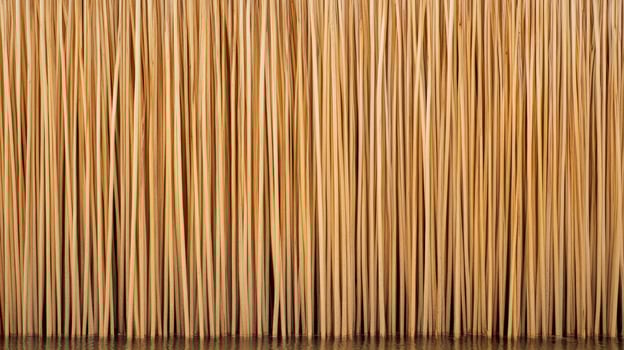 Close-up view of textured straw or grass fibers arranged vertically, highlighting natural patterns and warm tones photo