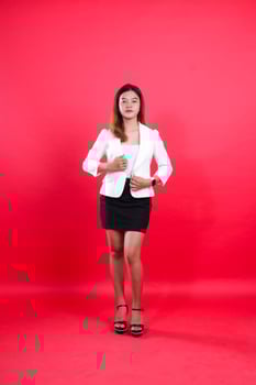 full body of beautiful young asian girl wearing elegant white suit both hands holding suit, standing isolated red background. for corporate, business, fashion content photo
