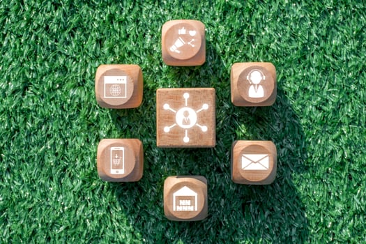 Wooden blocks with digital communication icons representing the omnichannel retail concept on a grass background. photo