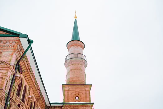 There is a brick building that features a green tower situated at the very top of its structure, creating a striking and memorable visual that stands out remarkably in the surrounding area photo