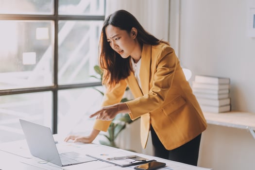 Young Asian businesswoman working on laptop computer, stressed has a headache and thinks hard from work photo