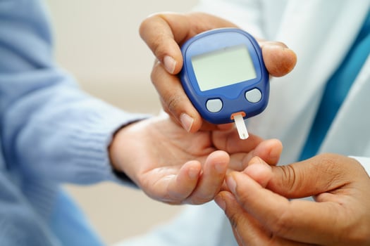 Asian doctor using digital glucose meter for check sample blood sugar level to photo