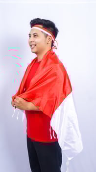 Handsome Young Indonesian Man Having Put on Indonesia Flag while Standing photo