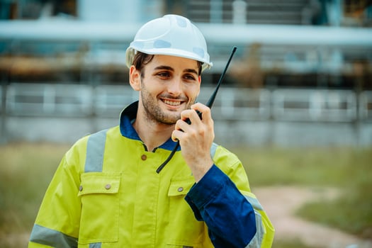 Construction worker communicates with team using walkie-talkie at industrial site during daytime photo