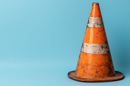 Old worn orange traffic cone on blue background photo