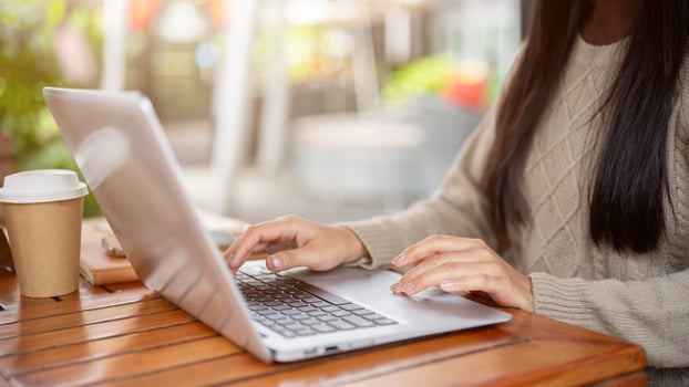 A close-up side view of a woman working on her laptop, working remotely from a cafe in the city. photo