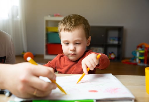 A cute little toddler boy of two years old with dad draws with markers in the album in the children's room at home. Spending time with children photo