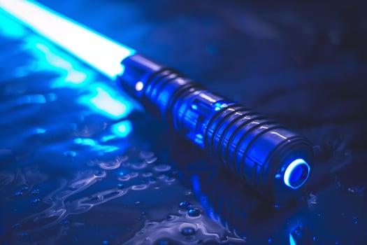 Blue light saber resting on wet surface reflecting light photo