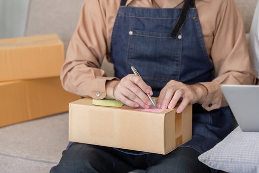Delivery professional labeling packages with notes in a cozy workspace, emphasizing attention to detail photo