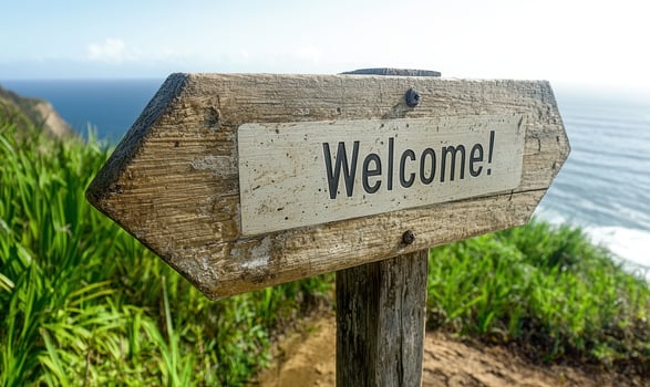 Wooden signpost with welcome message on a cliff overlooking the ocean photo