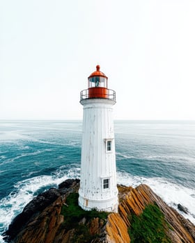 Lighthouse on a rocky coast with waves crashing against the rocks photo