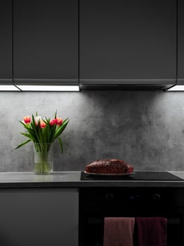 Prague kitchen counter displaying vibrant tulips, freshly baked cake, soft under cabinet lighting creating warm ambiance for Mother's Day Valentines copy space photo