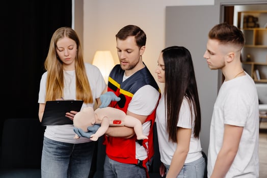 Group of people learning how to make first aid with dummy child during the training indoors. photo