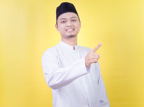 a man in a white shirt and hat pointing at something photo