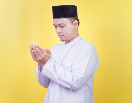 muslim man praying isoalted on yellow background photo